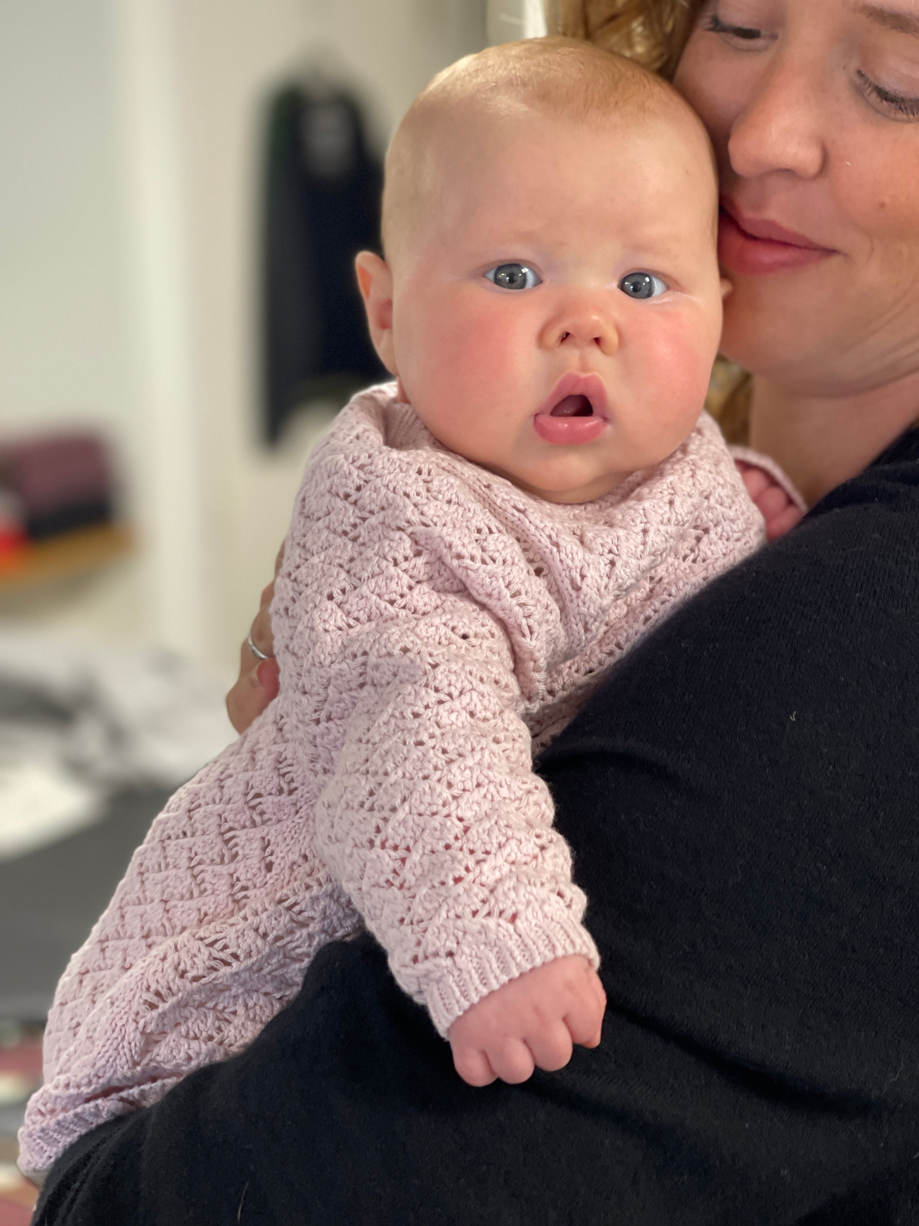 Baby in Bubblegum pink cardigan with wood buttons laying on grass 